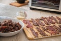 Asian style marinated raw beef strips for homemade jerky dried meat with sesame and chili on dehydrator drying tray, wooden board Royalty Free Stock Photo