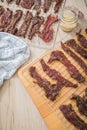 Asian style marinated raw beef strips for homemade jerky dried meat with sesame and chili on dehydrator drying tray, wooden board Royalty Free Stock Photo