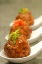 Asian styled meatballs on spoons with a variety of toppings