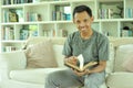 Asian successful male freelancer reading book at living room