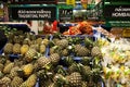 Asian supermarket shelf: pile of pineapples, bananas and other fruits. Thai and English market
