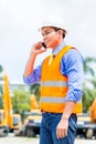 Asian supervisor telephoning on construction site