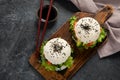 Asian sushi burger, soy sauce, chopstick on dark background. Trendy hybrid food