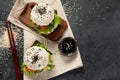 Asian sushi burger, soy sauce, chopstick on dark background. Trendy hybrid food