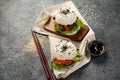 Asian sushi burger, soy sauce, chopstick on dark background. Trendy hybrid food