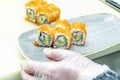 An Asian sushi chef assembling a tray with a uramaki california roll with masago roe Royalty Free Stock Photo