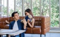 Asian sweet adorable couple sitting on sofa in living room at home, playing together, giving doll, smiling with happiness. Royalty Free Stock Photo