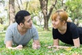 Asian sweet couple exercising together with smile on their faces on soft grass encircle with nature.