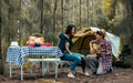 Asian sweet couple man and woman setting tent and camp in forest, playing guitar, adventure backpack traveling together with Royalty Free Stock Photo