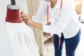 Asian tailor adjusts garment design on mannequin in workshop mak