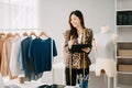 Asian tailor woman working on clothes in tailoring atelier. beautiful young female fashion designer smile and after success in