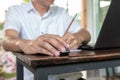 Asian tan skin holding wireless mouse on the vintage wood table and writting pencil with his left hand Royalty Free Stock Photo