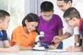 Asian teacher expanding to student in biology class with microscope . Royalty Free Stock Photo