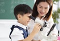 Teacher helps child to conduct experiment with microscope