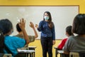 Asian teacher with protective face mask teaching her students on a class at elementary school after covid-19 quarantine and Royalty Free Stock Photo