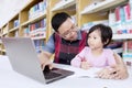 Asian teacher teaches female student in library