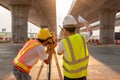 Asian Teamwork of civil engineer and surveyor engineers standing holding a blueprint making measuring with theodolite on road Royalty Free Stock Photo