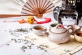 Asian teapot with teacups on bamboo tablamat decorated with chinese fan, lantern and scattered green tea on white marble Royalty Free Stock Photo