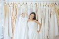 Asian teen bride trying on wedding dress,Woman designer making adjustment in wedding dress shop