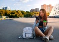 Asian Teen Girl with coffee Looking On Mobile Phone In Urban Setting