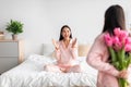 Asian teen girl with tulips bouquet, back and happy young female sitting on bed in bedroom interior