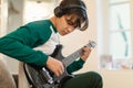 Asian Teen Guy Playing Electric Guitar Wearing Headphones At Home Royalty Free Stock Photo