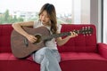 Asian teen playing acoustic guitar relax on sofa in living room, enjoy leisure weekend at home. Stress free concept Royalty Free Stock Photo