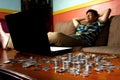 Asian Teen relaxing in front of laptop computer and a stack of coins Royalty Free Stock Photo