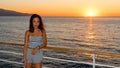 Asian teen in tube top standing on deck of ferry looking away from sunset Royalty Free Stock Photo