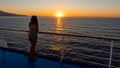 Asian teen in tube top standing on deck of ferry looking at sunset