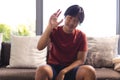 Asian teenage boy sitting on couch at home, making hand gesture during a video call Royalty Free Stock Photo