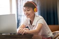 Asian teenage boy studying at home wearing headset and smiling Royalty Free Stock Photo