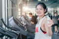 Asian teenage braces girl cardio training exercise in sport club with towel on her shoulders smiling after workout on treadmill in Royalty Free Stock Photo