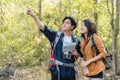 Asian teenage couples hold a map and point with hand. Couple of young tourist hiking in a forest Royalty Free Stock Photo