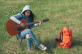 Asian teenage girl playing guitar happily Alone in the green fields and soft evening light.
