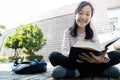 Asian teenage girl student holding a book in her hands and preparing for the exam reading book,schoolgirl reading textbook outdoor Royalty Free Stock Photo