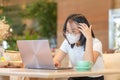 Asian teenage girl typing on a laptop in a coffee shop, Girl working at her laptop Royalty Free Stock Photo