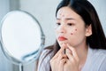 Asian teenage woman  looking at mirror and squeeze acne problem Royalty Free Stock Photo