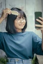 Asian teenager combing forelock hair by comb and smartphone screen