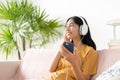 Asian teenager listen to music on smartphone with headphone enjoy. Asia woman using mobile phone happy smile relax at home Royalty Free Stock Photo