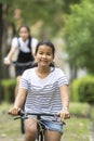 Asian teenager riding a bicycle in green public park