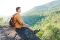 Asian teenager sitting on cliff bridge edge and looking at the mountain