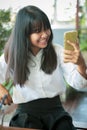 Asian teenager smiling with happiness looking to smart phone screen Royalty Free Stock Photo