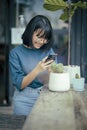 Asian teenager taking a photo of cactus pot by mobile phone