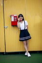 Asian teenager talking to old model of public telephone against yellow sync wall Royalty Free Stock Photo