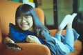 Asian teenager toothy smiling face lying on sofa and  holding smart phone in hand Royalty Free Stock Photo