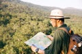 Asian teenager using compass with paoer map to hike through forest to peak of mountain Royalty Free Stock Photo