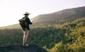 Asian teenager using compass with paper map to hike through forest to peak of mountain Royalty Free Stock Photo