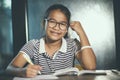 Asian teenager wearing eye glasses doing home work with stack of Royalty Free Stock Photo