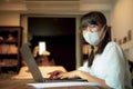 Asian teenager wearing protection mask quarantine at home and working on computer laptop